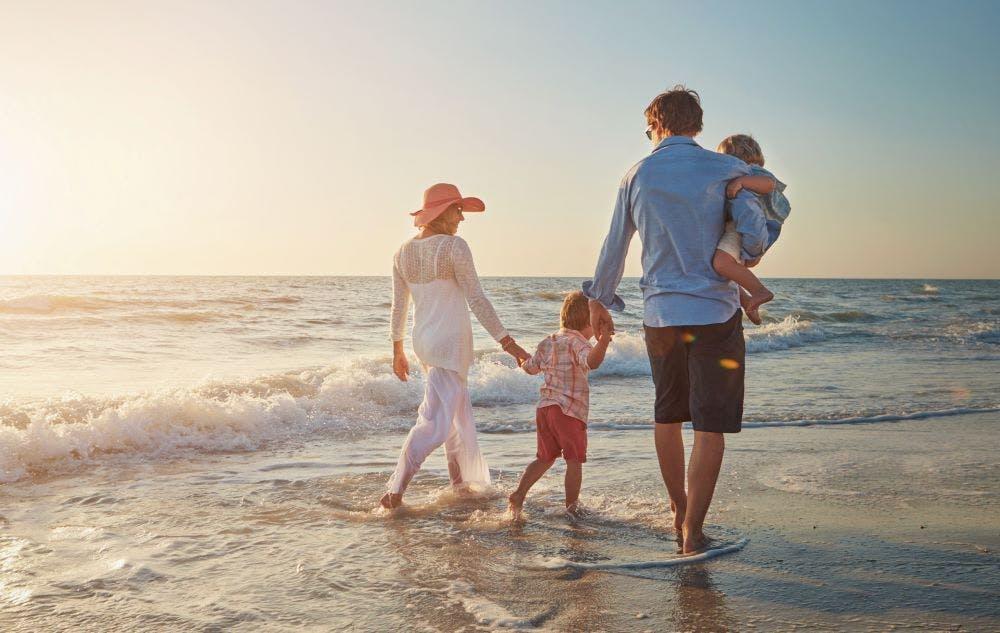 A family holding hands and walking down the beach 